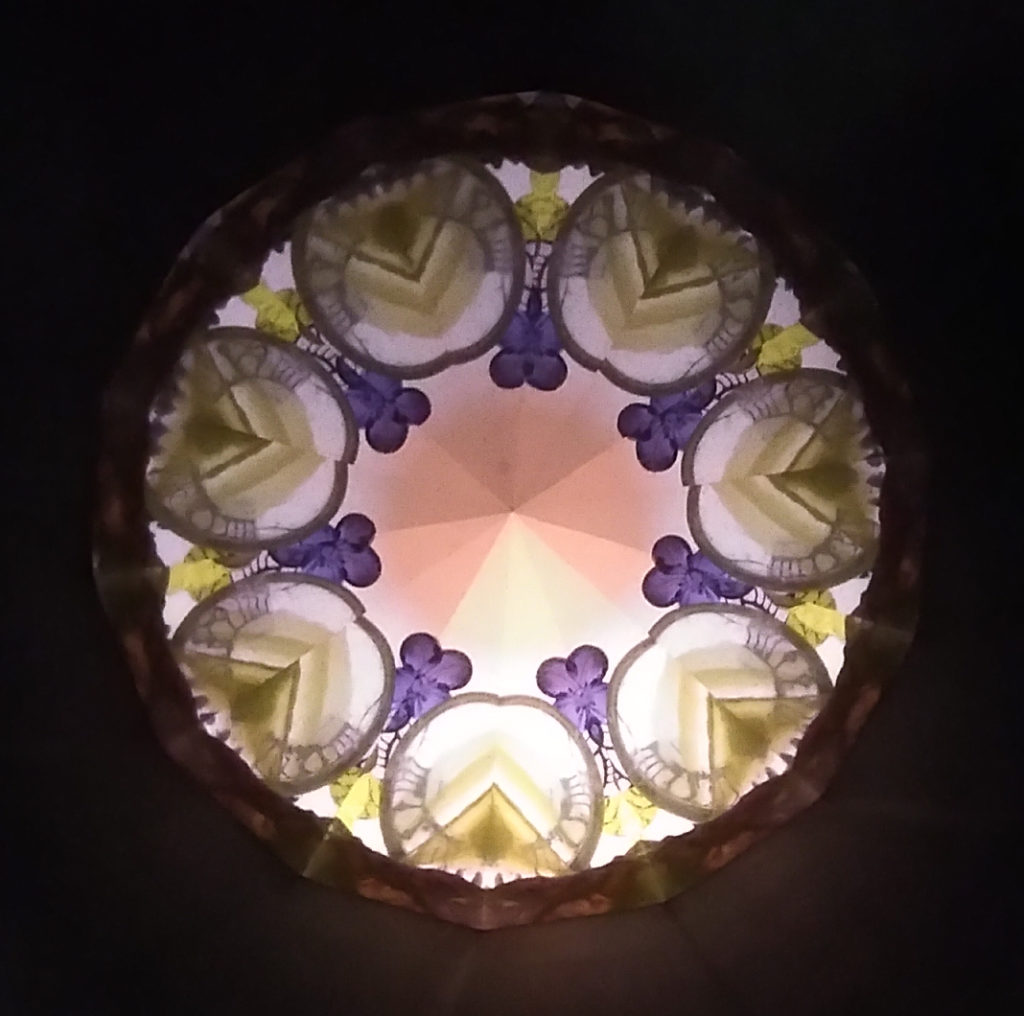 Kaléidoscopie, cœur octogonal lumineux, 8 pétales violets vers le centre. Sur l'extérieur, 8 formes vertes et blanches faisant penser à des artichauts.